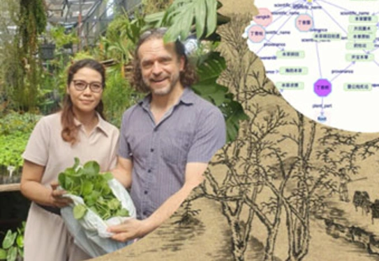 Two people inside a greenhouse revealing a green plant in a bag.