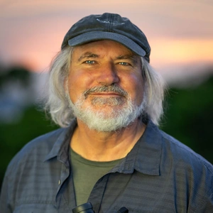 A smiling person with a white beard.