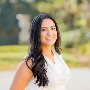 A smiling person in a sunny garden.