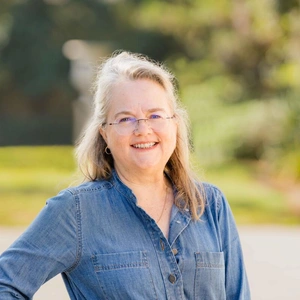 A smiling person in a sunny garden.