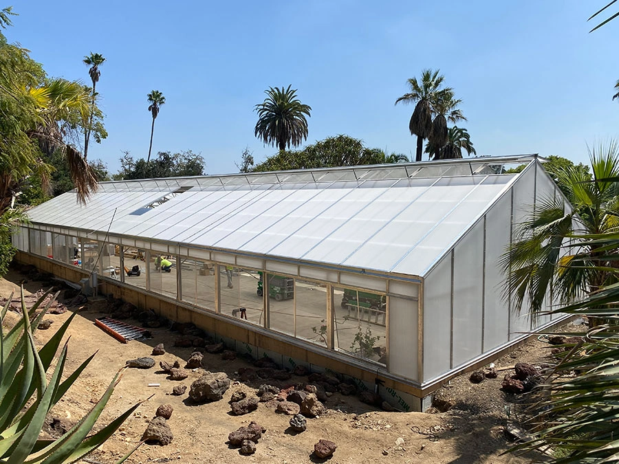 Workers and materials can be seen through the windows of a large conservatory under construction.