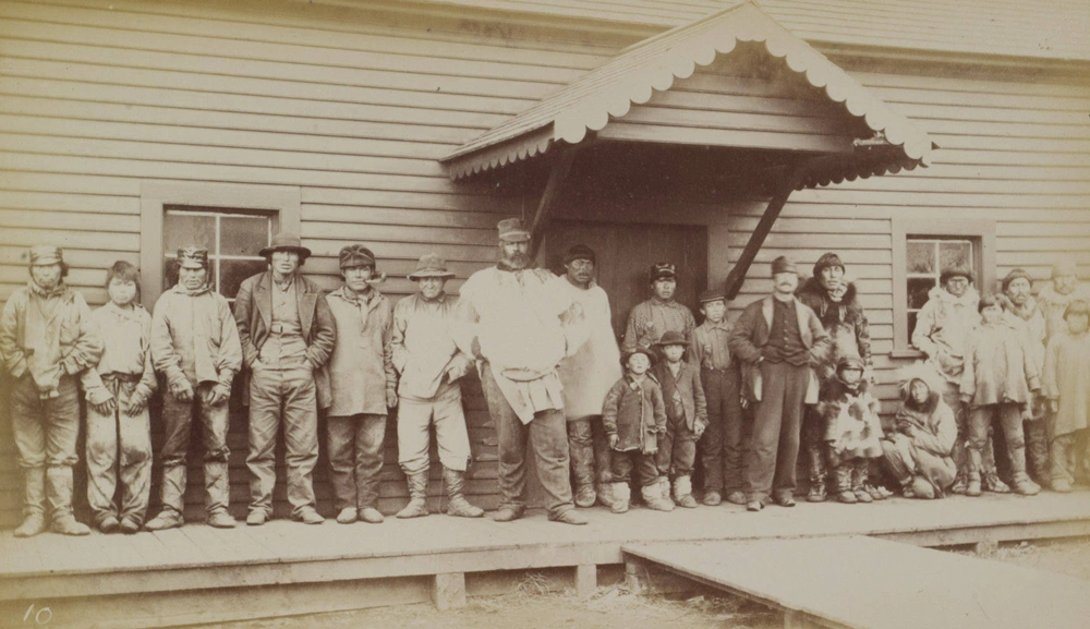 A large group of people stand in a row in front of a building.